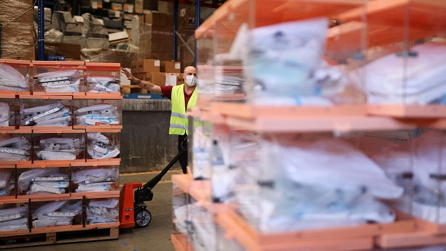 Un trabajador mueve urnas de votos con equipos de protección individual (EPI) para los colegios electorales catalanes en Barcelona