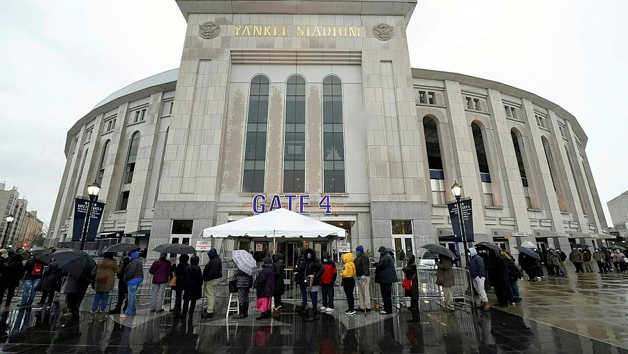 Varias personas esperan en el exterior del estadio de los Yankees, en Nueva York, para recibir la vacuna de la COVID.