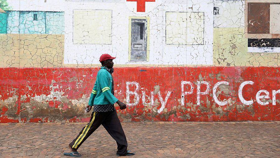 Un hombre, sin mascarilla, camina bajo un mural de un hospital en Soweto, Sudáfrica.