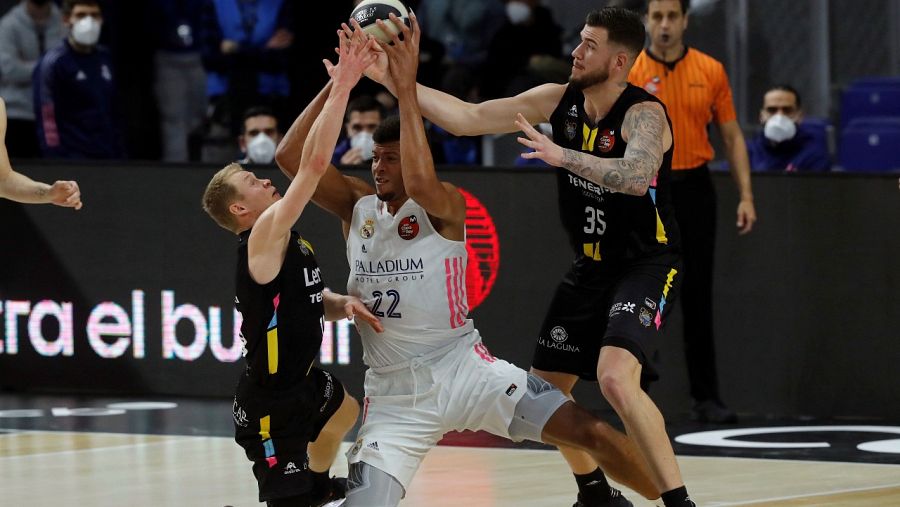 El escolta finlandés Sasu Salin (i) y el pívot Fran Guerra (d), del Lenovo Tenerife, luchan por la posesión del balón ante el pívot caboverdiano del Real Madrid Walter 'Edy' Tavares (c).