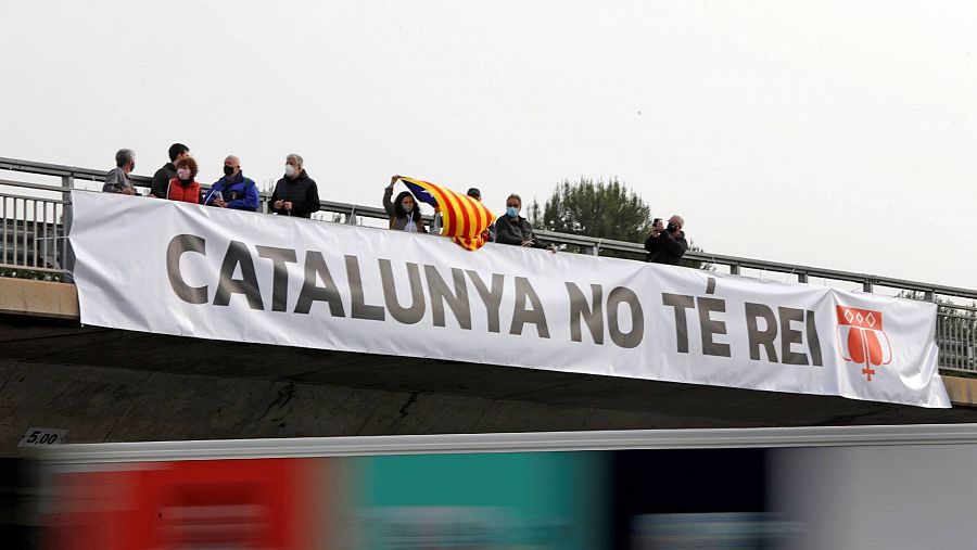 Un grupo de manifestantes colocan en un puente una pancarta en protesta por la presencia del Rey