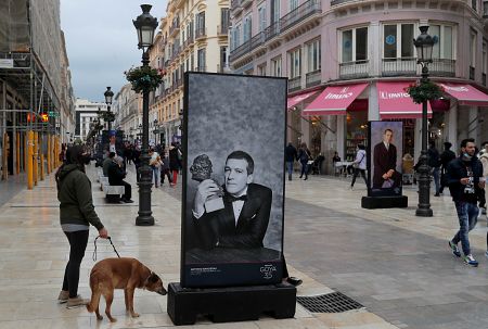 Varias personas pasean junto a un mural con una imagen de Antonio Banderas.