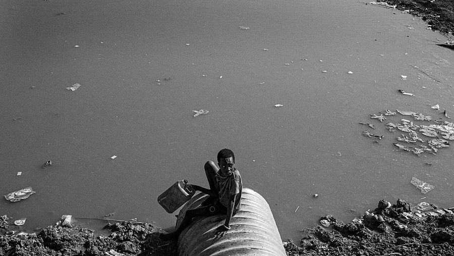 Un joven sentado en una alcantarilla en el campo de desplazados de Bentiu