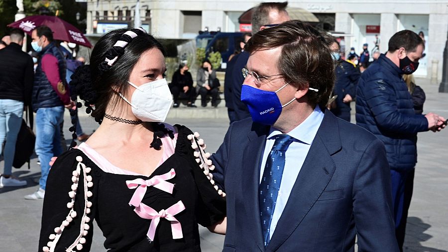 El alcalde de Madrid, José Luis Martínez Almeida, saluda a una mujer vestida con un traje tradicional durante un acto de precampaña del PP.