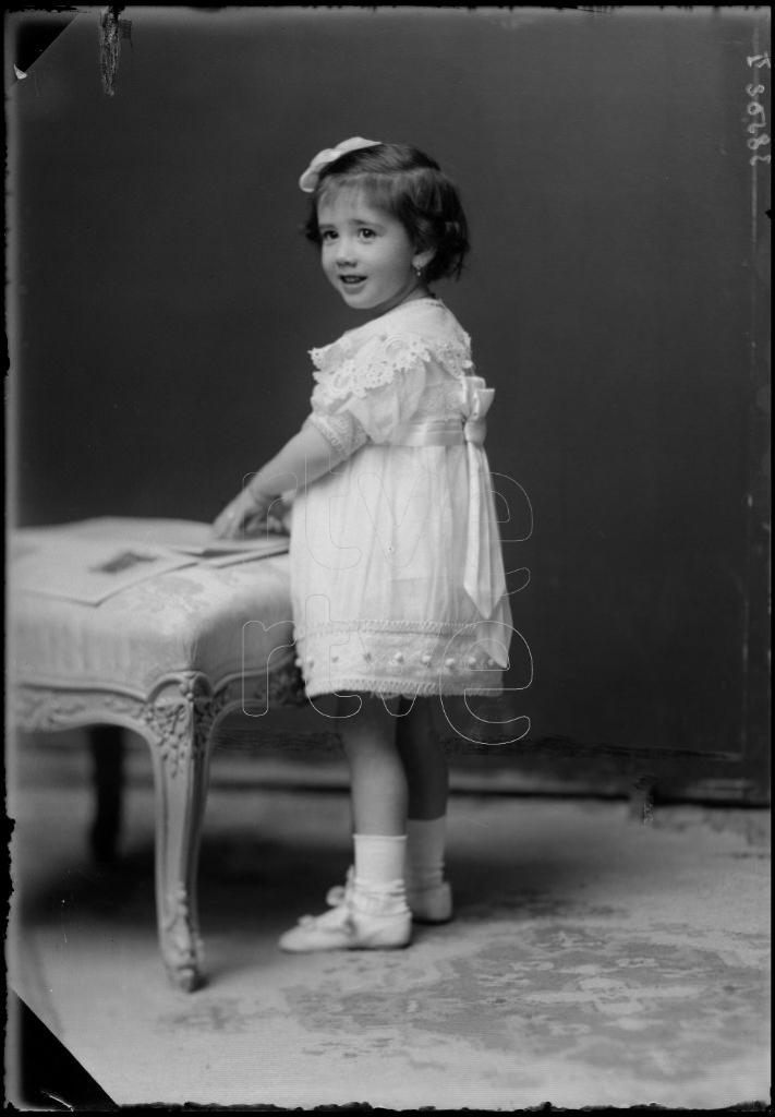 NI&Ntilde;A DE CORTA EDAD CON UNA REVISTA APOYADA EN UN ESCABEL