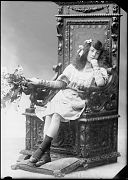 NIÑA CON UN RAMO, SENTADA EN UN SILLON DE MADERA LABRADA