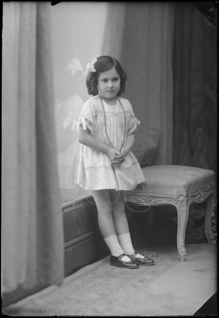 NI&Ntilde;A DE CORTA EDAD DE PIE JUNTO A UN VENTANAL