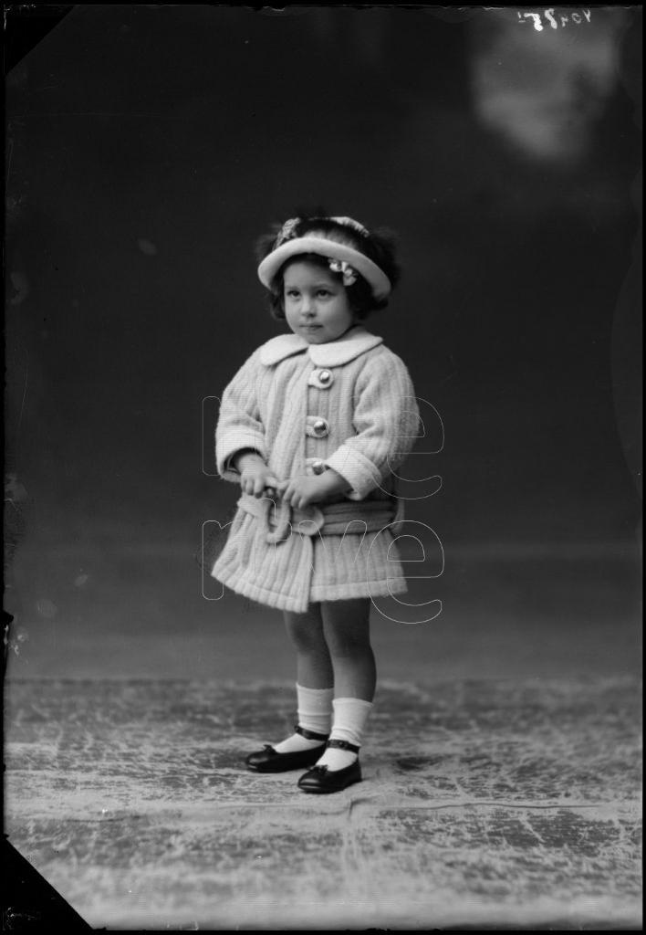 NIÑA DE CORTA EDAD CON UN ABRIGO Y UN SOMBRERO