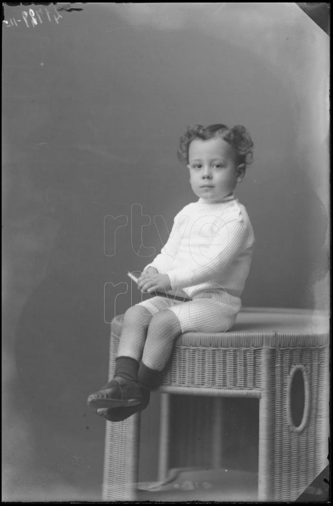 NIÑO DE CORTA EDAD CON UN LIBRO, SENTADO EN UNA MESA