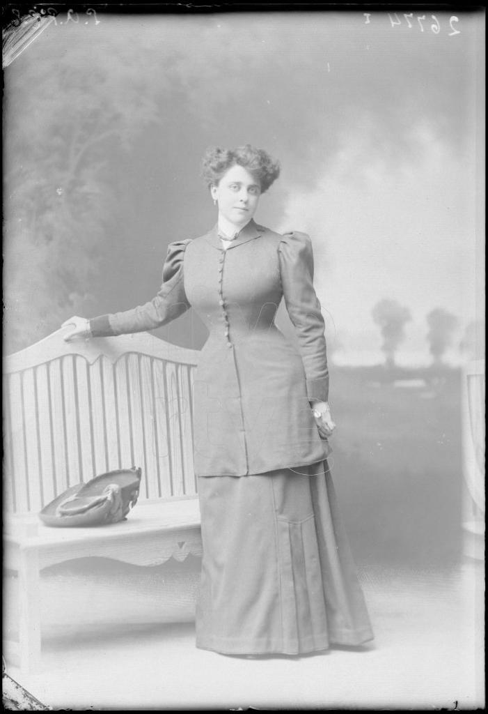 MUJER DE PIE JUNTO A UN BANCO