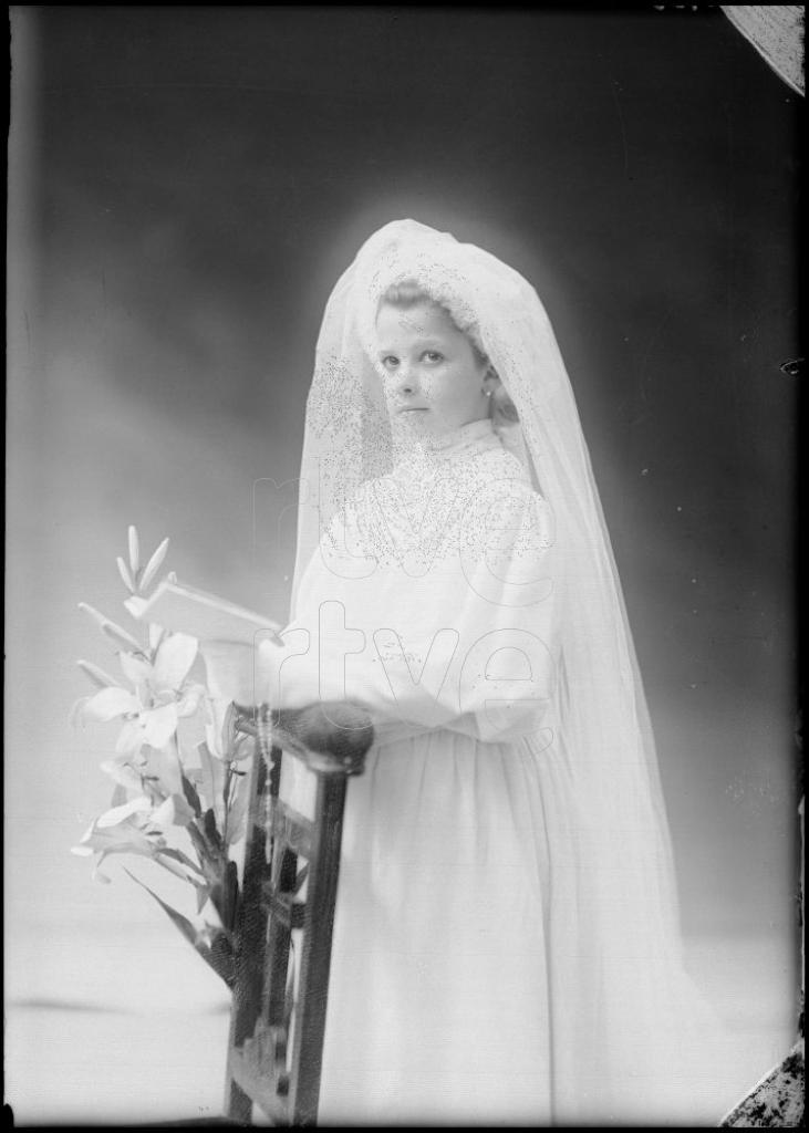 NI&Ntilde;A VESTIDA DE PRIMERA COMUNION, APOYADA EN UN RECLINATORIO