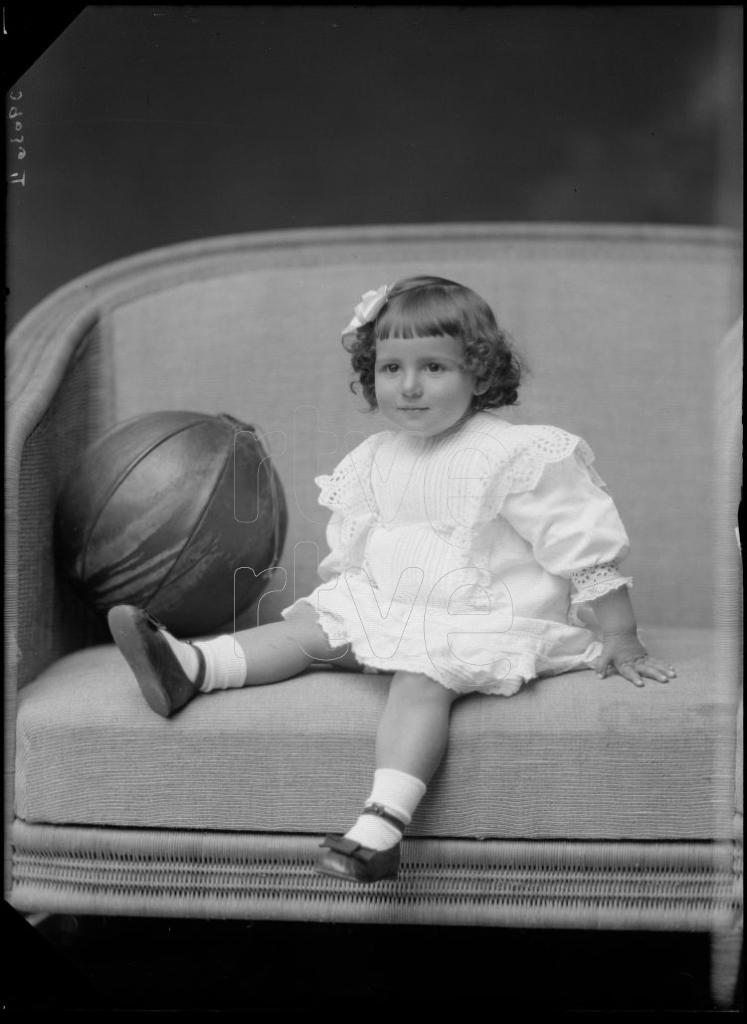 NIÑA DE CORTA EDAD SENTADA JUNTO A UN BALON