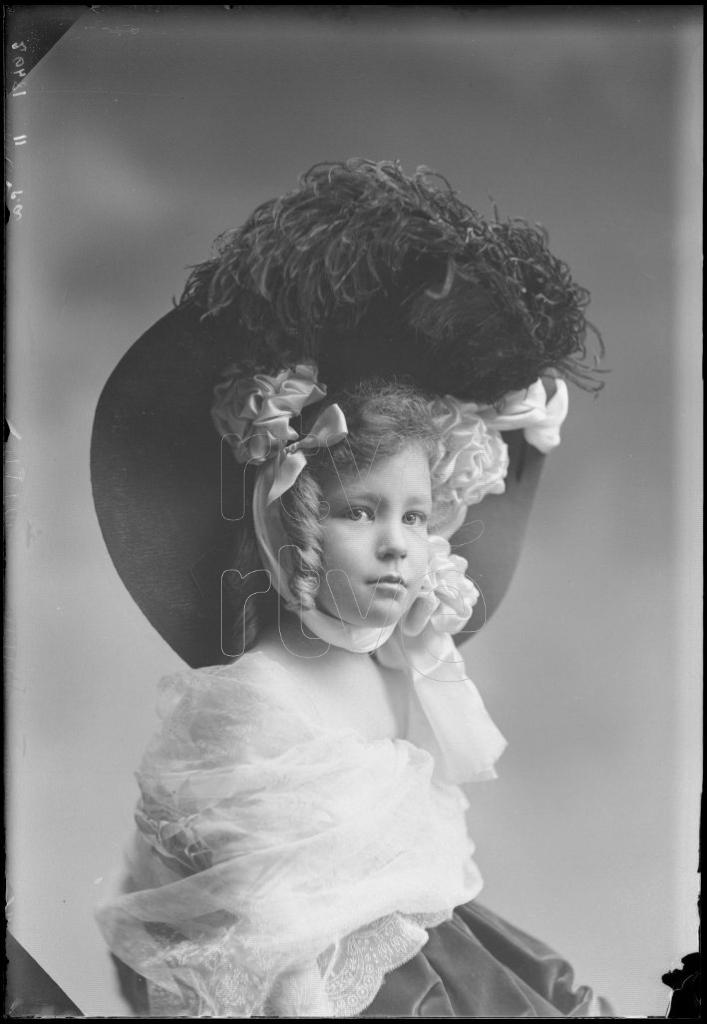 NIÑA DE CORTA EDAD CON UN GRAN SOMBRERO Y UN CHAL, SENTADA D