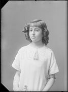 NIÑA APOYADA EN EL RESPALDO DE UNA SILLA