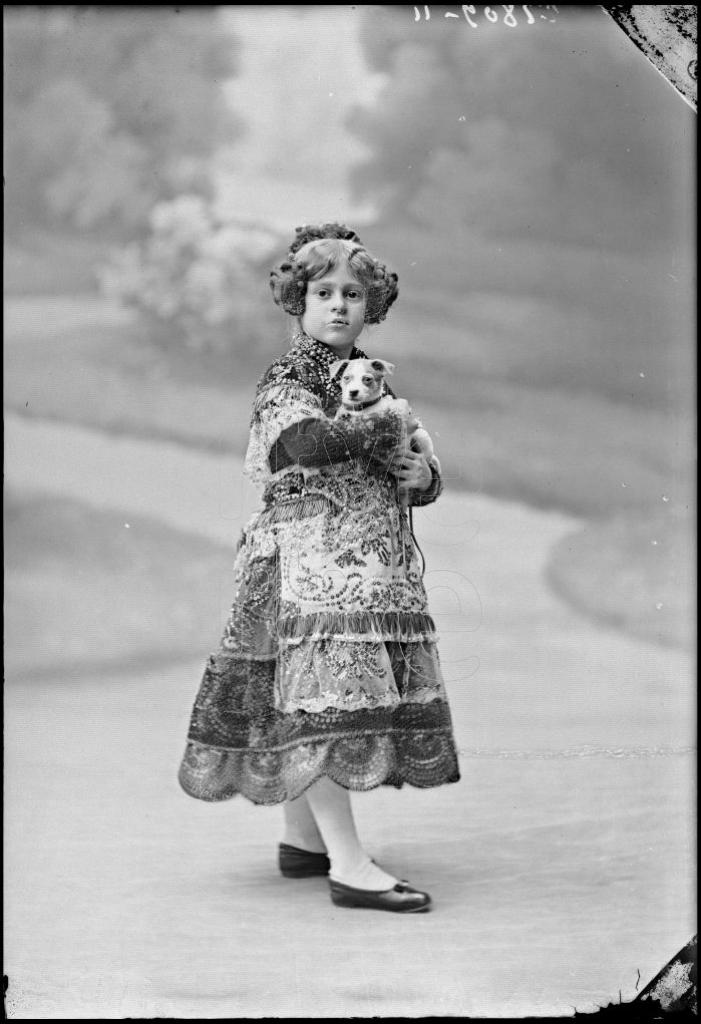 NI&Ntilde;A VESTIDA CON UN TRAJE REGIONAL Y UN PERRO EN BRAZOS