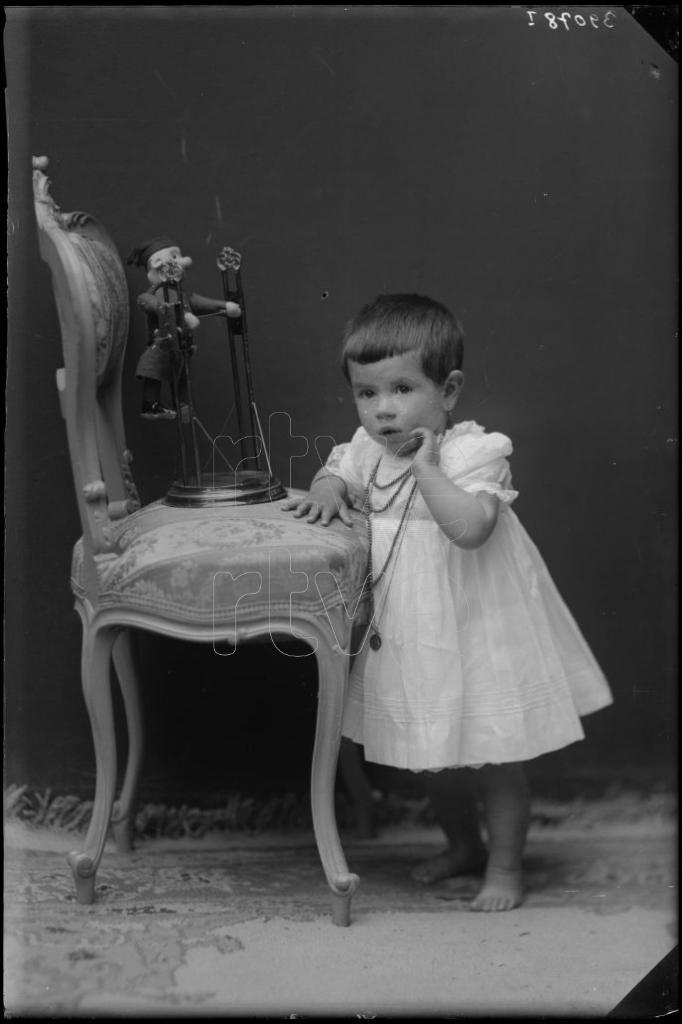 NIÑA DE CORTA EDAD CON UN JUGUETE EN UNA SILLA