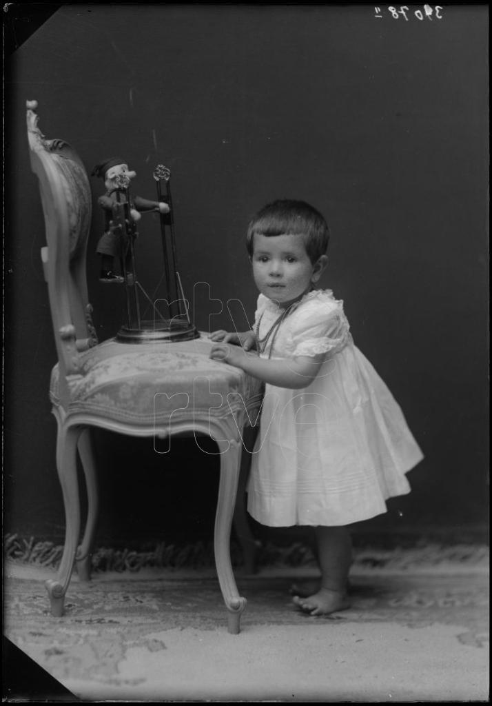 NIÑA DE CORTA EDAD CON UN JUGUETE EN UNA SILLA