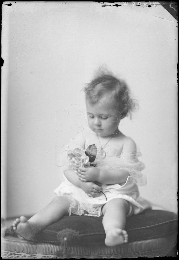 NIÑA DE CORTA EDAD CON UNAS FLORES EN LAS MANOS, SENTADA