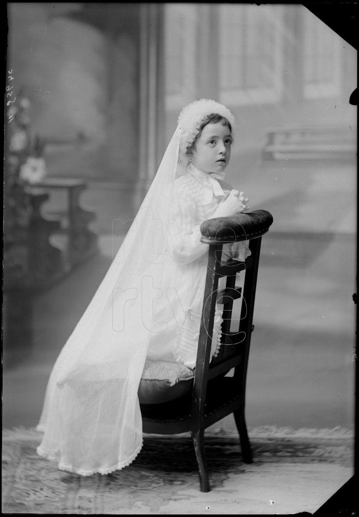 NI&Ntilde;A VESTIDA DE PRIMERA COMUNION, ARRODILLADA EN UN RECLINAT