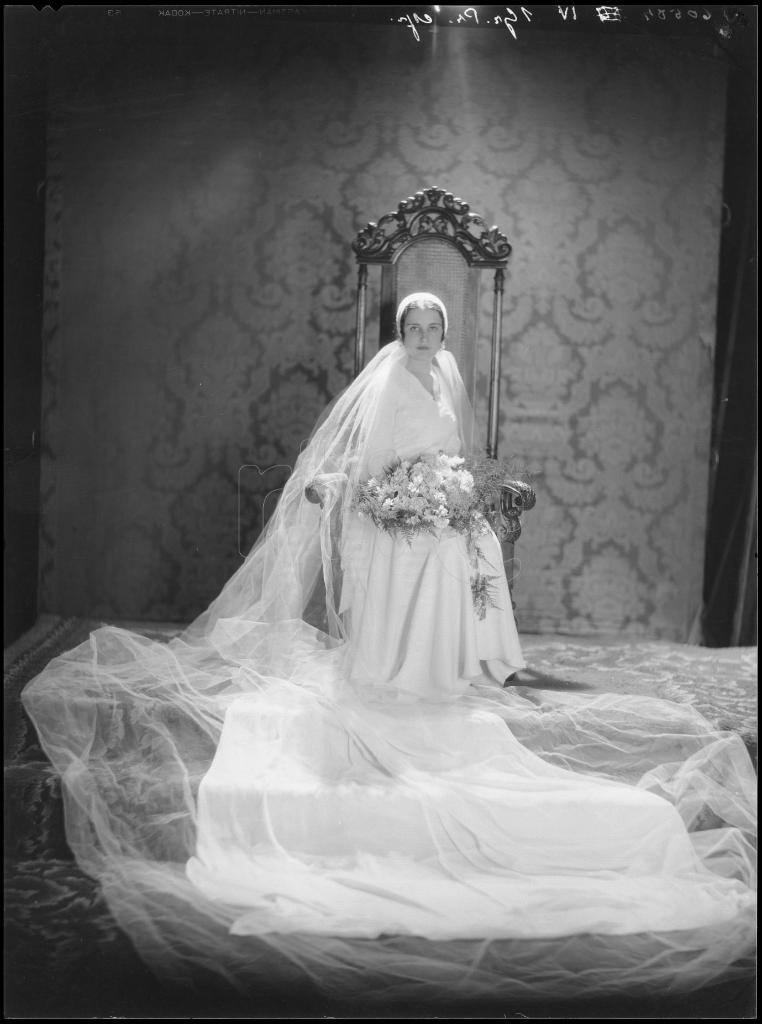 NOVIA CON UN VESTIDO CON COLA, EL VELO LARGO Y UN GRAN RAMO,