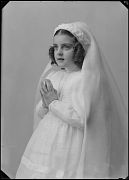 NIÑA VESTIDA DE PRIMERA COMUNION CON LAS MANOS JUNTAS EN POS