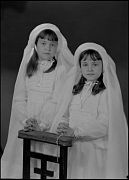 DOS NI&Ntilde;AS VESTIDAS DE PRIMERA COMUNION, APOYADAS EN UN RECLI