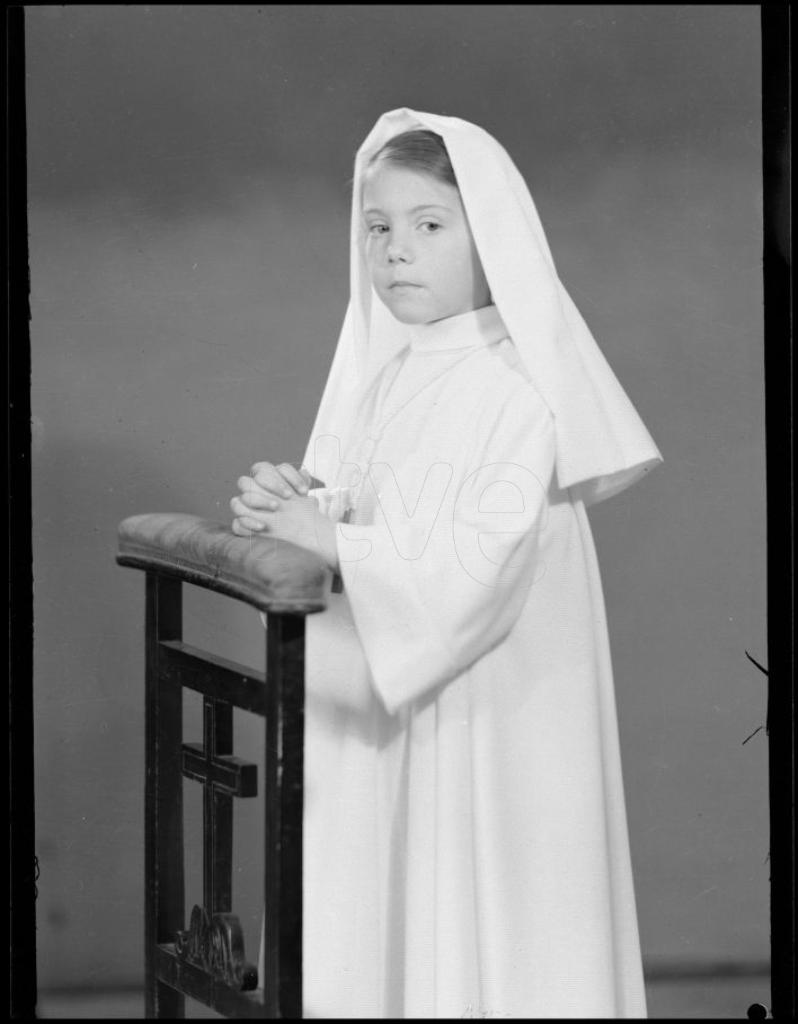 NI&Ntilde;A VESTIDA DE PRIMERA COMUNION, APOYADA EN UN RECLINATORIO