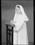 NI&Ntilde;A VESTIDA DE PRIMERA COMUNION, APOYADA EN UN RECLINATORIO