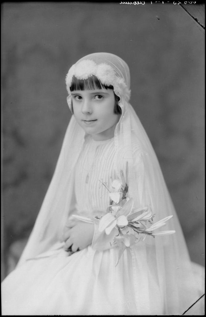 NIÑA VESTIDA DE PRIMERA COMUNION CON UN RAMO, SENTADA 