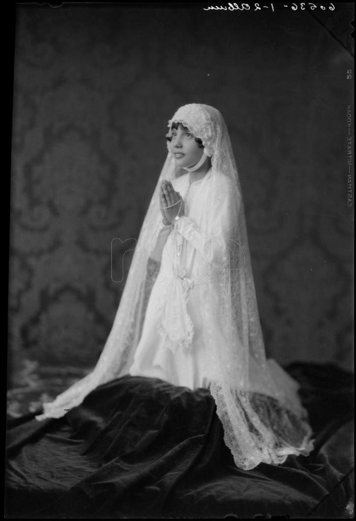 NIÑA VESTIDA DE PRIMERA COMUNION, ARRODILLADA CON LAS MANOS 