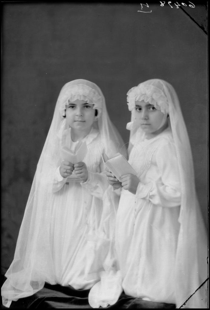 DOS NIÑAS VESTIDAS DE PRIMERA COMUNION, ARRODILLADAS