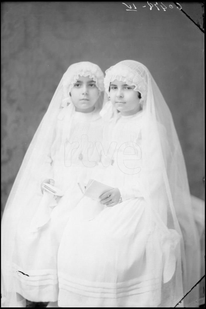 DOS NIÑAS VESTIDAS DE PRIMERA COMUNION, SENTADAS