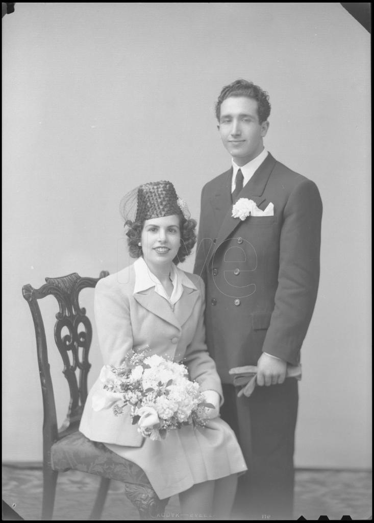 NOVIA CON UN SOMBRERO CON REDECILLA Y UN TRAJE DE FALDA Y CH