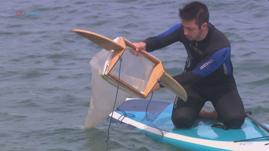 Un voluntari de Surfing for science amb la xarxa per atrapar microplàstics