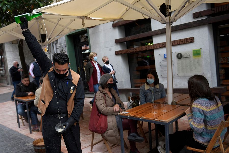 Un camarero escancia sidra en una terraza llena de gente en la Plaza del Fontán, en Oviedo.