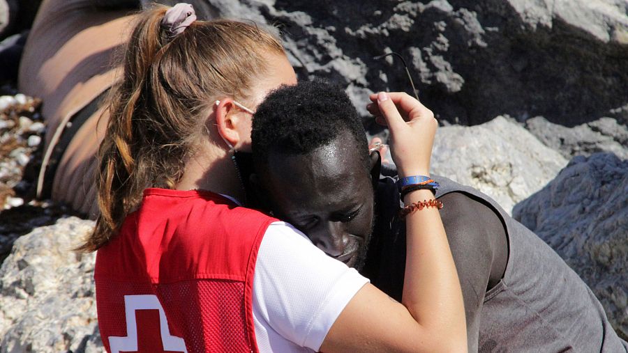 Una trabajadora de la Cruz Roja y un migrante se abrazan