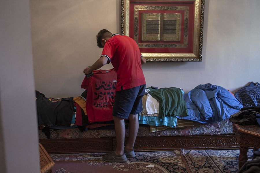 Un joven busca ropa de su talla en casa de Sabah.