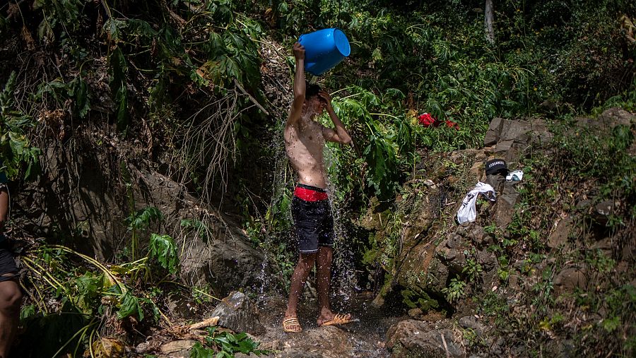 Hafid duchandose en una fuente de agua en medio del bosque