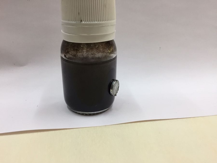 Aspecto de una suspensión de partículas de magnetita para que un imán se adhiera a un recipiente.