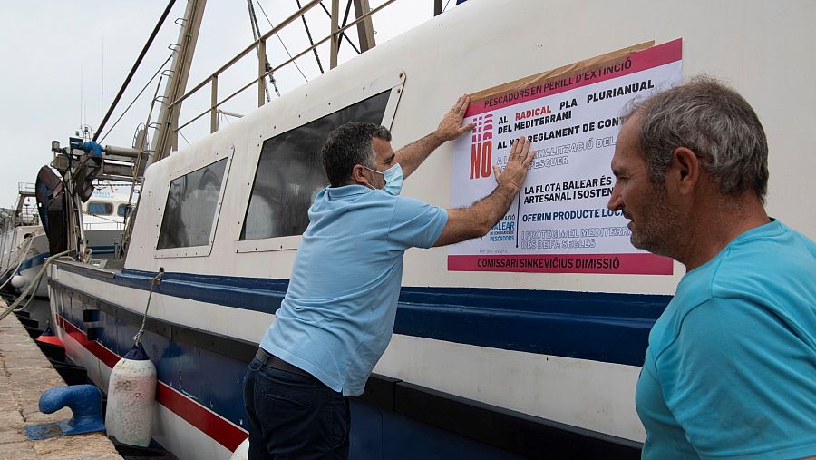 Un pescador coloca un cartel reivindicativo en su barco