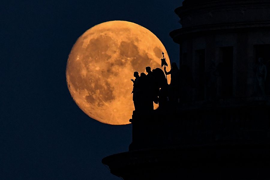 La luna llena de la fresa, detrás de las esculturas de la catedral de San Isaac en San Petersburgo