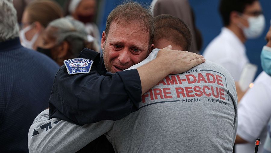 Dos miembros del equipo de rescate de Miami se abrazan emocionados durante un homenaje a las víctimas