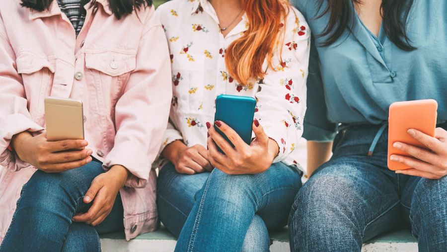 Tres jóvenes fotografiadas mientras utilizan sus teléfonos móviles