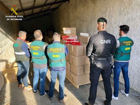 Agentes de la Guardia Civil junto a cajas con cigarrillos incautados en una operación