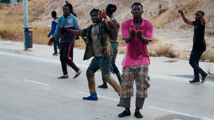 Varios migrantes celebran haber conseguido saltar la valla fronteriza