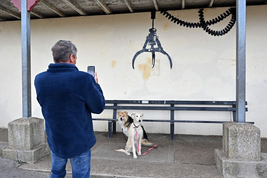 Un hombre fotografía a sus perros bajo el grafiti de un gancho aparecido en Gorleston-on-Sea