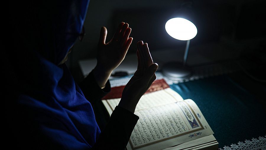 Mujere musulmana rezando con el Corán