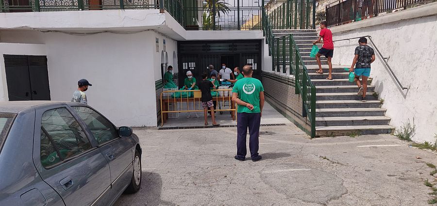 Varios menores recogen una bolsa con comida.