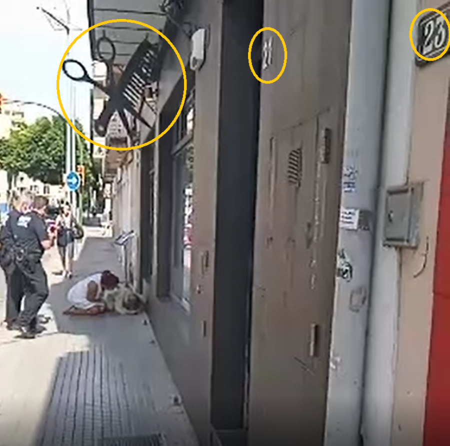 Imagen del vídeo en el momento que se ven los rótulos del 21 y el 23, junto con las tijeras y el peine del rótulo de la peluquería