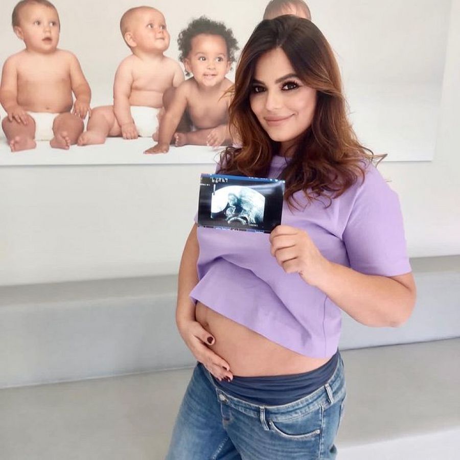 Marisa Jara posa tocándose la tripa con una ecografía de su bebé